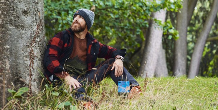 Aldio Kane sat by a tree wearing the Fjӓllrӓven Clothing Range