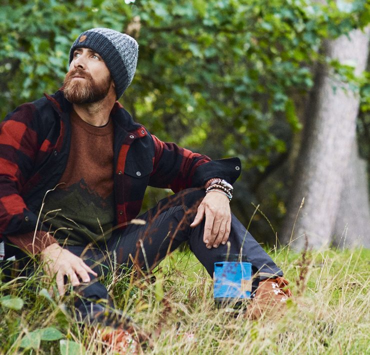 Aldio Kane sat by a tree wearing the Fjӓllrӓven Clothing Range