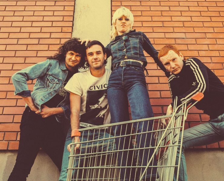 Band Amyl and the Sniffers posing for a photo with lead singer Amy in a shopping trolley