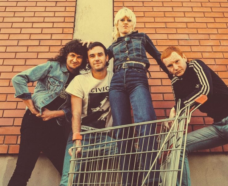 Band Amyl and the Sniffers posing for a photo with lead singer Amy in a shopping trolley