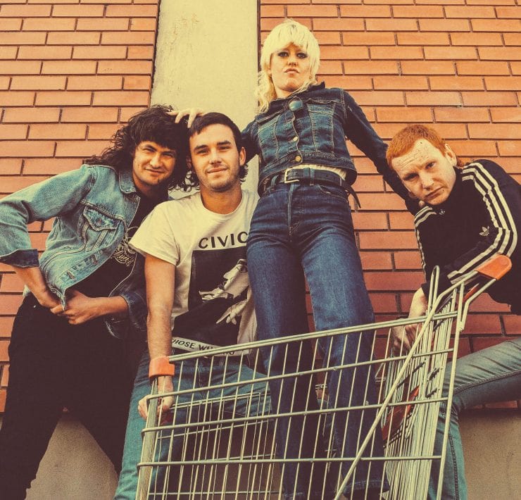 Band Amyl and the Sniffers posing for a photo with lead singer Amy in a shopping trolley
