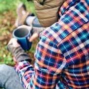 A man sits in the woods drinking coffee