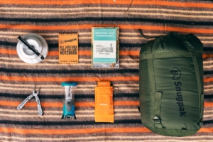 A selection of outdoor essentials laid out on a patterned blanket