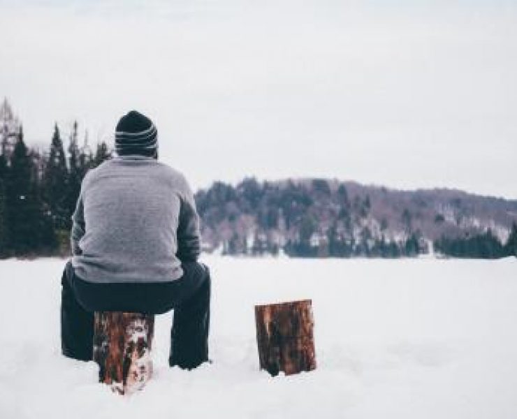 A man sat on a log in the snow