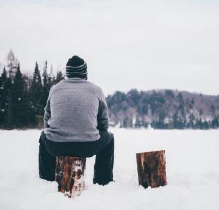 A man sat on a log in the snow