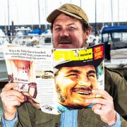Ian Shaw dressed as Quint reading a film magazine with his father's face on the cover