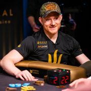 Poker player Jason Koon smiles as he throws chips onto the table