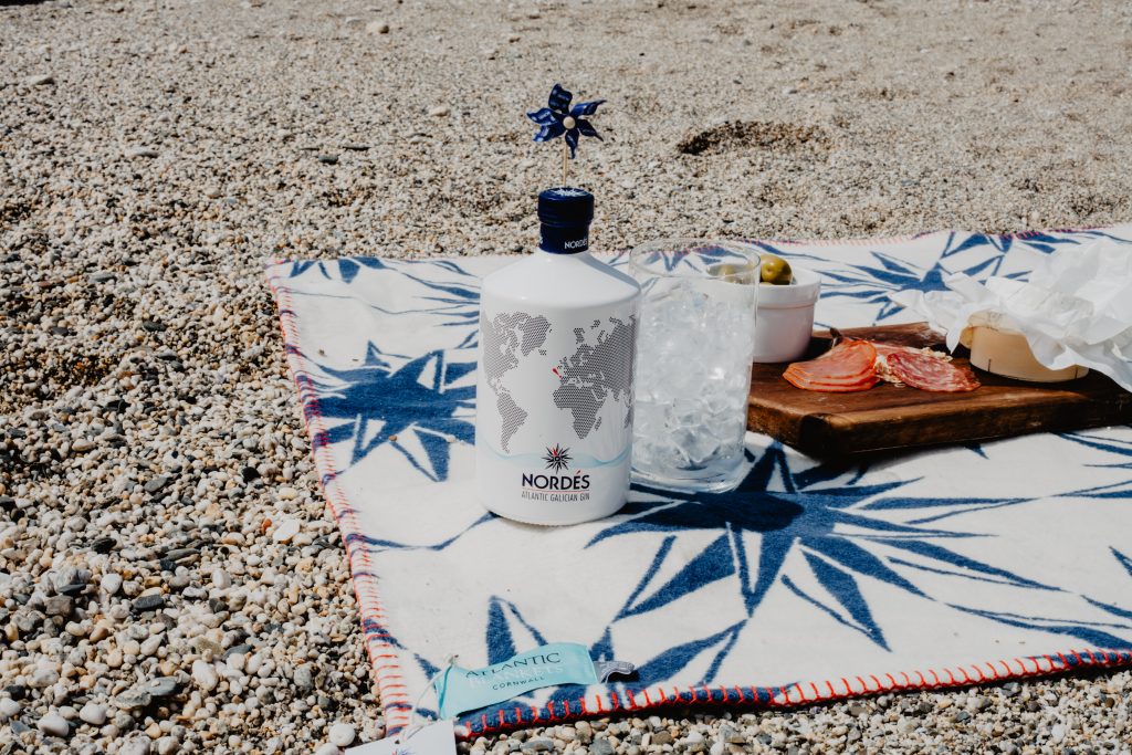 A bottle of Nordes Gin sat next to a glass on an Atlantic Blanket