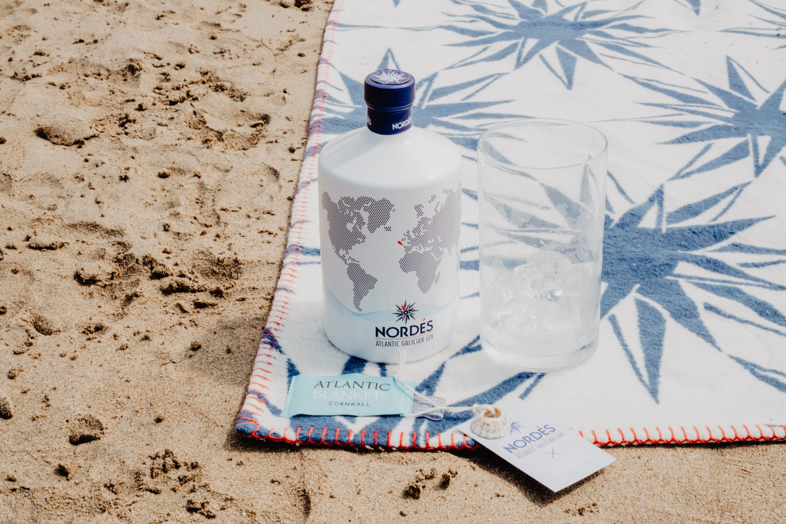 A bottle of Nordes Gin sat next to a glass on an Atlantic Blanket