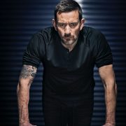 Ollie Ollerton stands with his hands on a desk