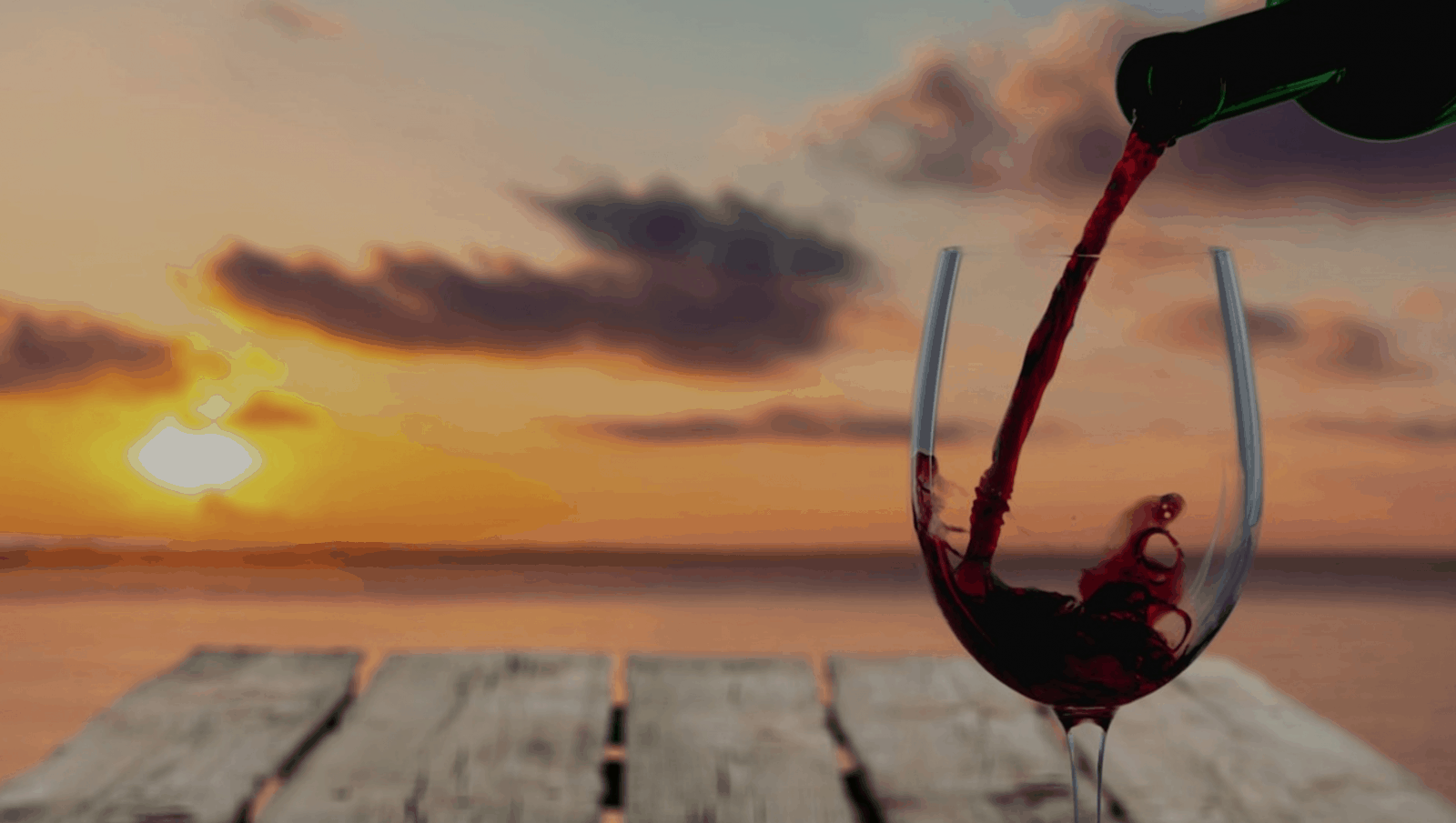 A glass of wine being poured at sunset