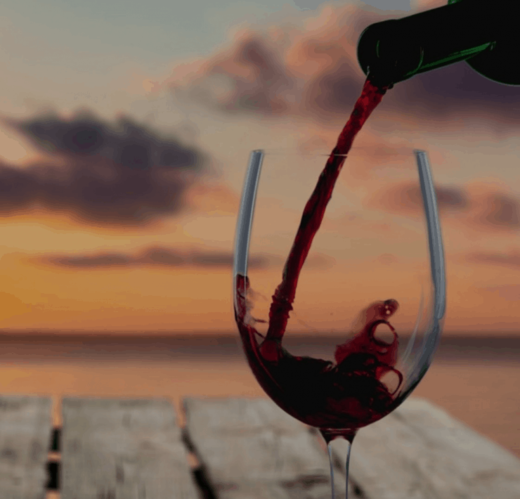 A glass of wine being poured at sunset
