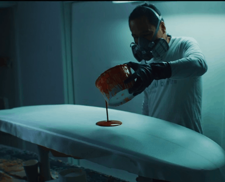 man pouring paint on a surfboard