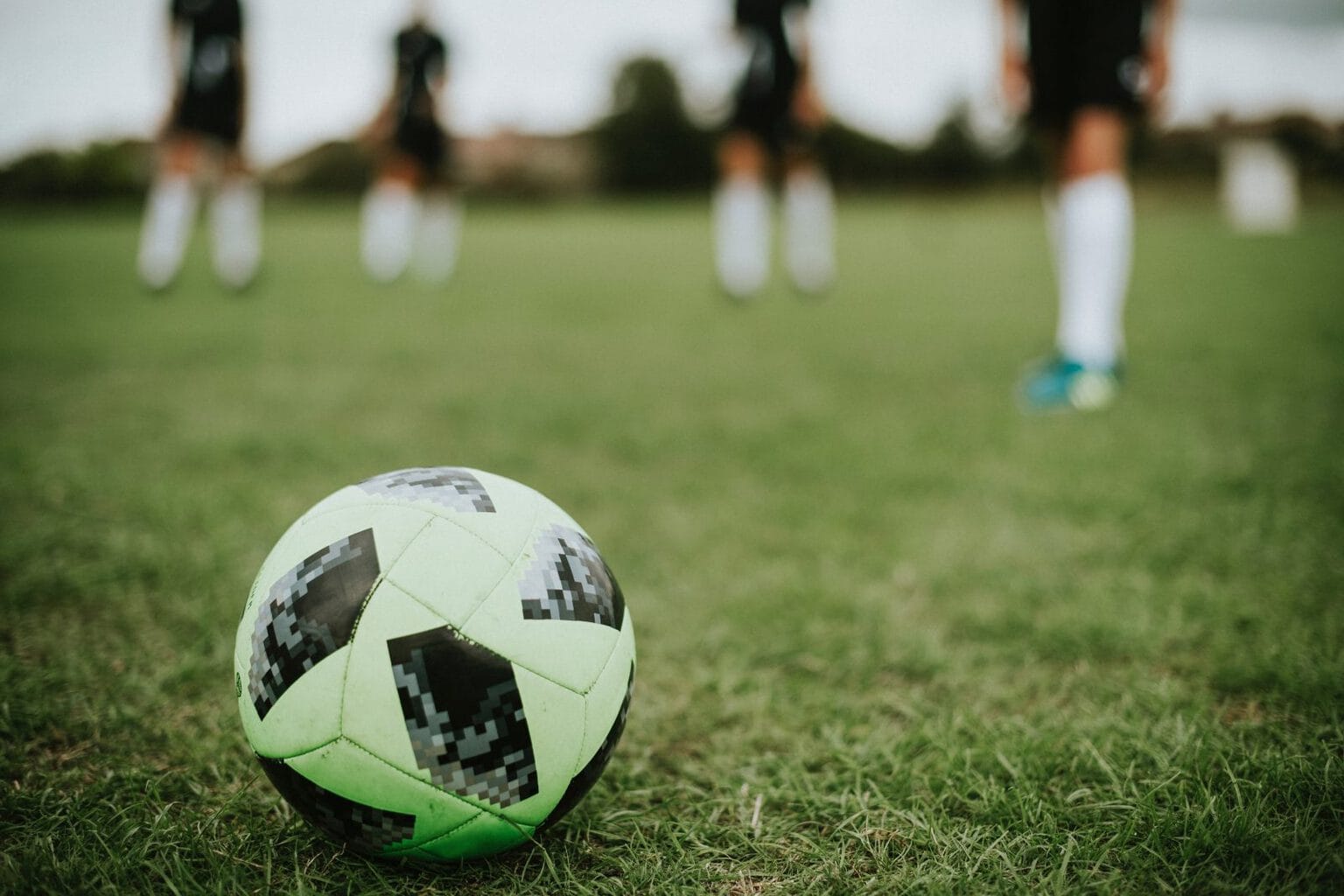 Football on pitch with four players in the background