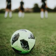 Football on pitch with four players in the background