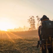 A man carrying a backpack observes the sunrise