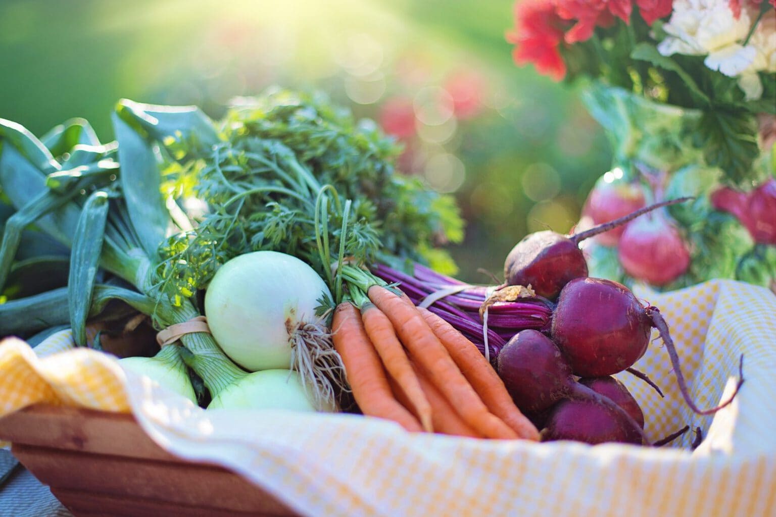 A basket full of vegetables, carrots, red onions