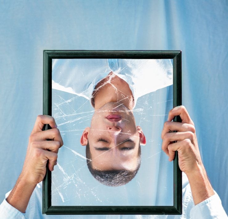 A man's reflection in a broken mirror