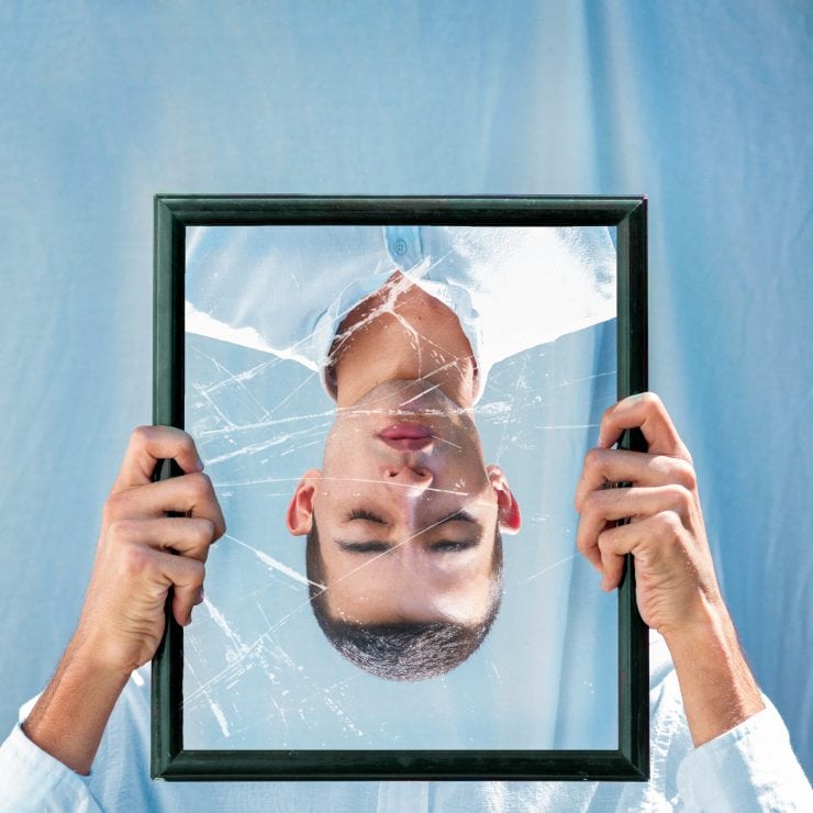 A man's reflection in a broken mirror