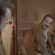 Jean Dujardin looks in a mirror at himself from a scene from Deerskin