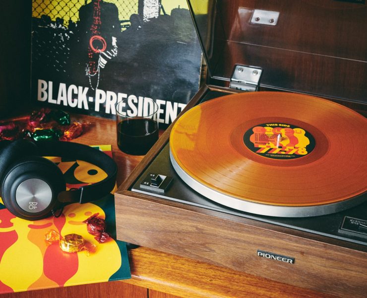 Record player with 77:78 record on it next to headphones