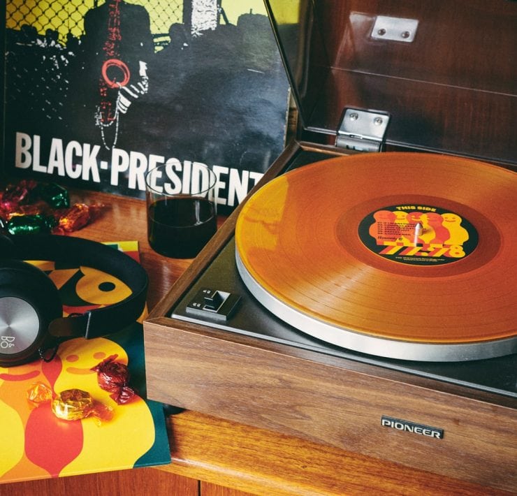 Record player with 77:78 record on it next to headphones