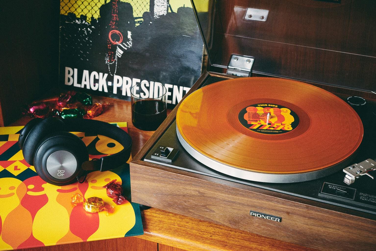 Record player with 77:78 record on it next to headphones