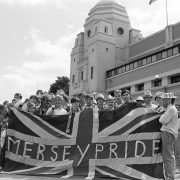 Liverpool fans outside wembley in 80s with flag saying "Merseypride'