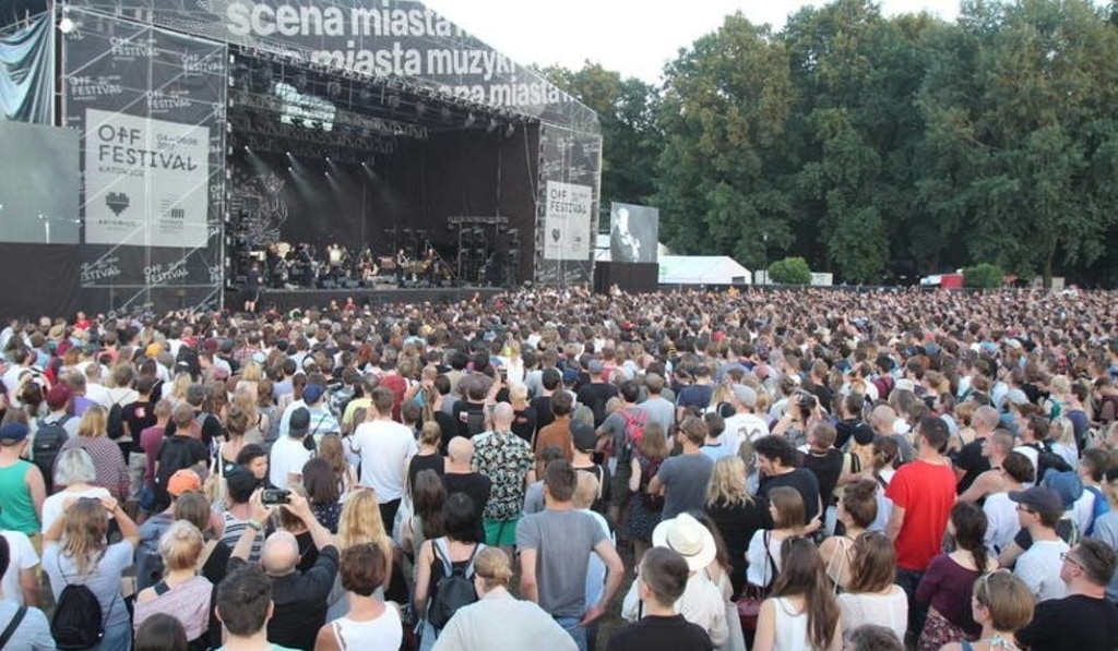 Crowds of people gathered round a stage watching a band perform